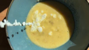 Echando la leche en la mezcla de plátano para la masa de los gofres