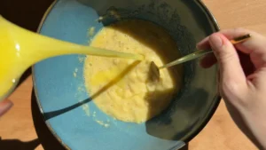Añadiendo la mantequilla derretida a la mezcla de plátano y huevo mientras se remueve