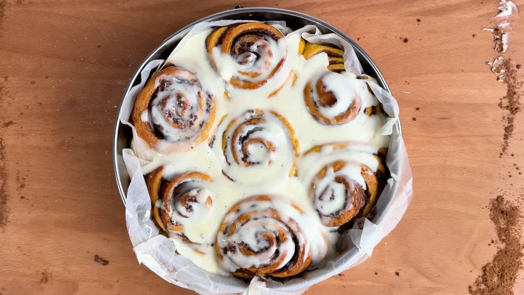 Cinnamon rolls de calabaza con frosting de queso crema en un molde redondo