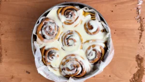 Cinnamon rolls de calabaza con frosting de queso crema en un molde redondo