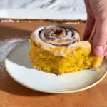 Kürbis-Zimtschnecken: aufgezupfte Schnecke mit Frosting auf dem Teller