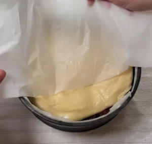 Colocando el disco de masa de brioche sobre la fruta y retirando el papel de horno