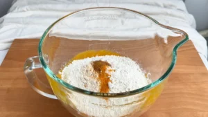 Harina, canela y cúrcuma sobre la mezcla de puré de calabaza en el bol de la amasadora