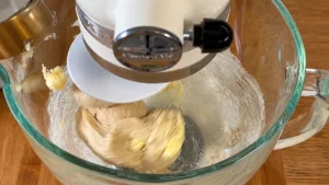 Añadiendo la mantequilla blanda a la masa de brioche en la amasadora