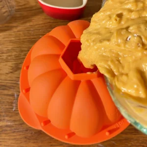 Vertiendo la masa del bizcocho de calabaza por el agujero del molde de calabaza 3D de silicona