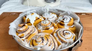 Regando con nata los cinnamon rolls de calabaza levados, antes de hornearlos