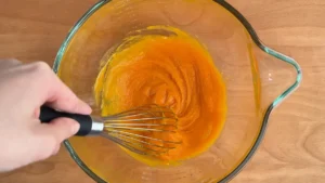 Mezclando el puré de calabaza con el huevo y el azúcar con unas varillas