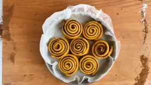 Siete rollos de canela de calabaza en el molde redondo, antes del segundo levado