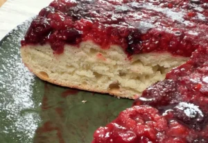 Tarta brioche de masa madre cortada, con la miga esponjosa y los frutos rojos caramelizados por encima