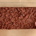 Turrón de chocolate crujiente casero recién desmoldado, sostenido con las dos manos